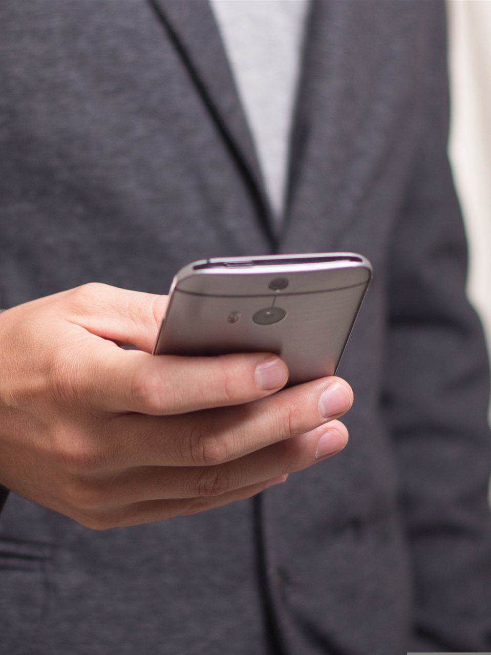 Mann hält ein Handy in der Hand und bedient es