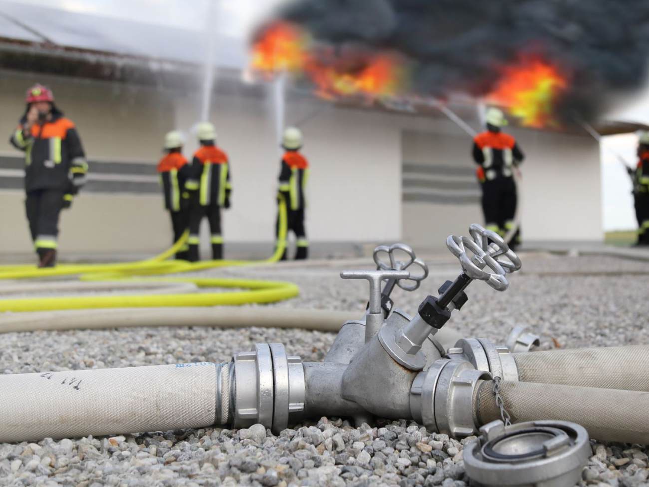 Ein Fabrikgebäude steht in Flammen und die Feuerwehr löscht