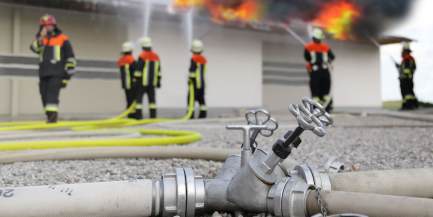 Ein Fabrikgebäude steht in Flammen und die Feuerwehr löscht