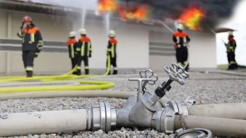 Sabotage durch Feuer im Unternehmen Ein Fabrikgebäude steht in Flammen und die Feuerwehr löscht