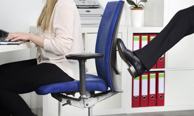 Ein Kollege tritt gegen den Stuhl einer Mitarbeiterin und mobbt sie